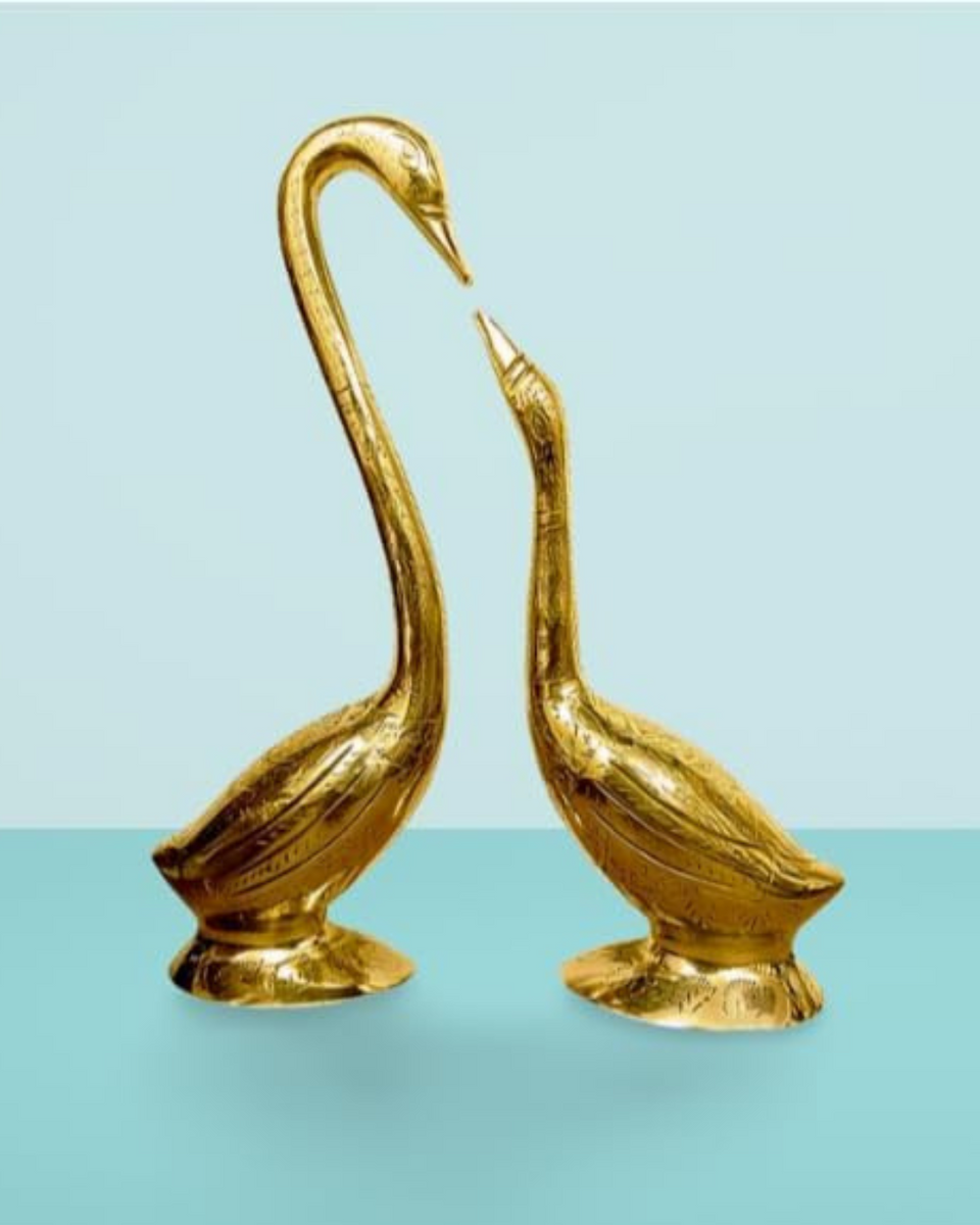 Two gold swan statues on a light blue background