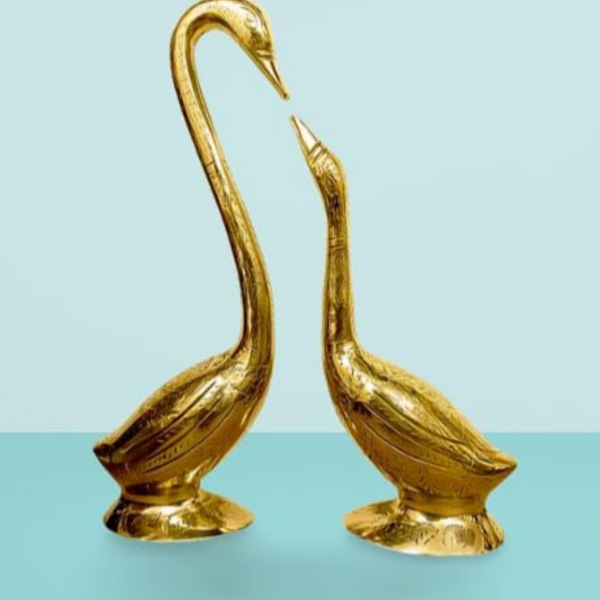 Two gold swan statues on a light blue background